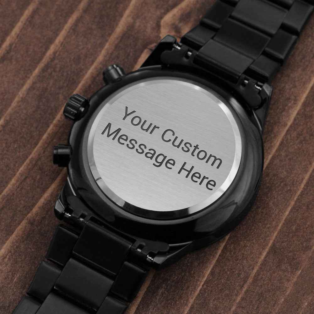 Black metal wristwatch with customizable engraved back plate on wooden surface