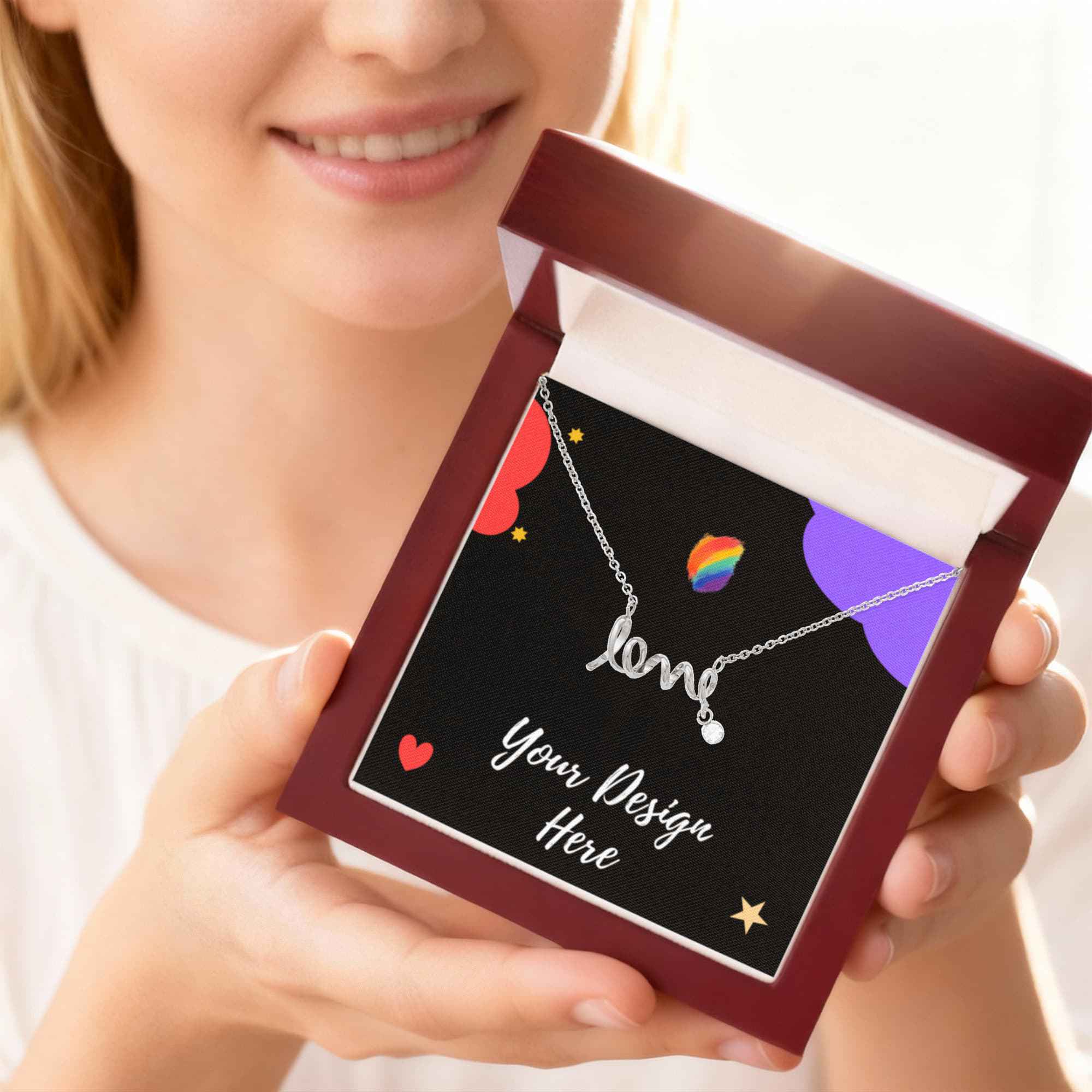 Smiling woman holding open jewelry box with silver 'love' necklace on colorful card