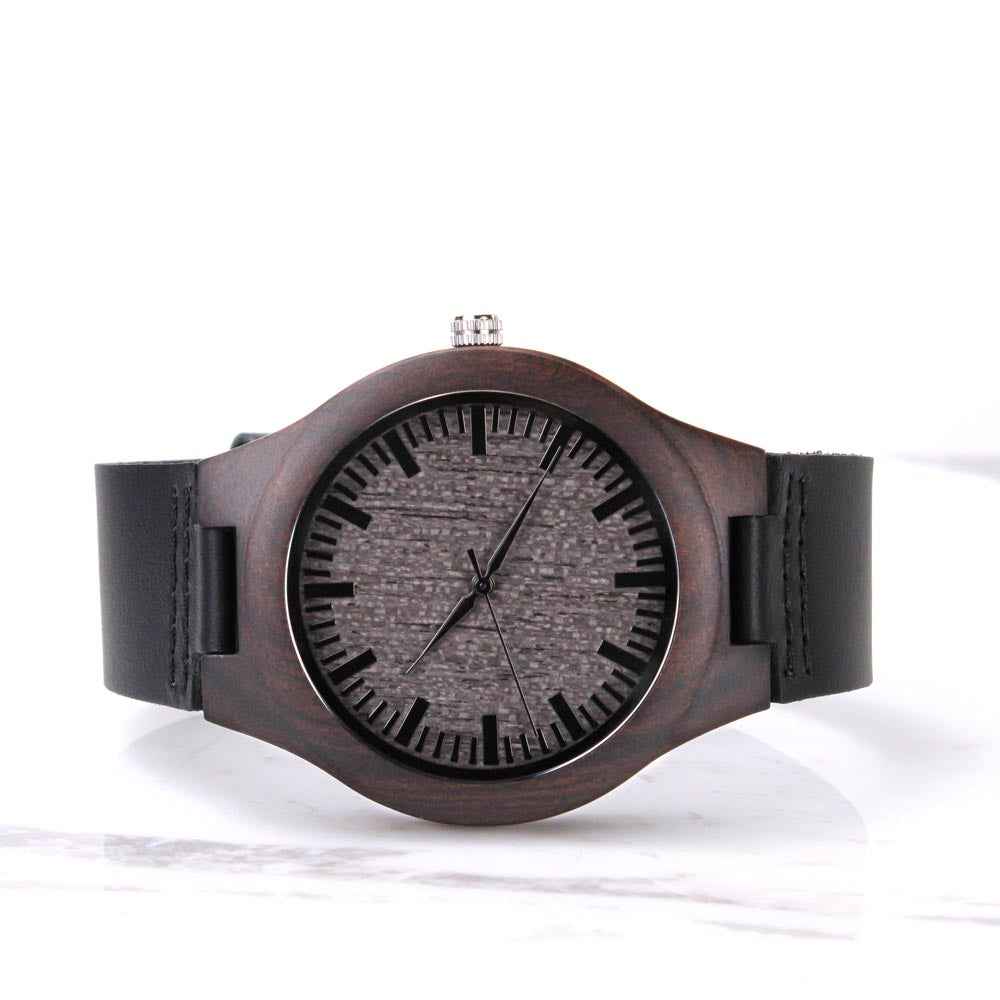 Minimalist wooden wristwatch with black leather strap and textured dark gray dial on white background