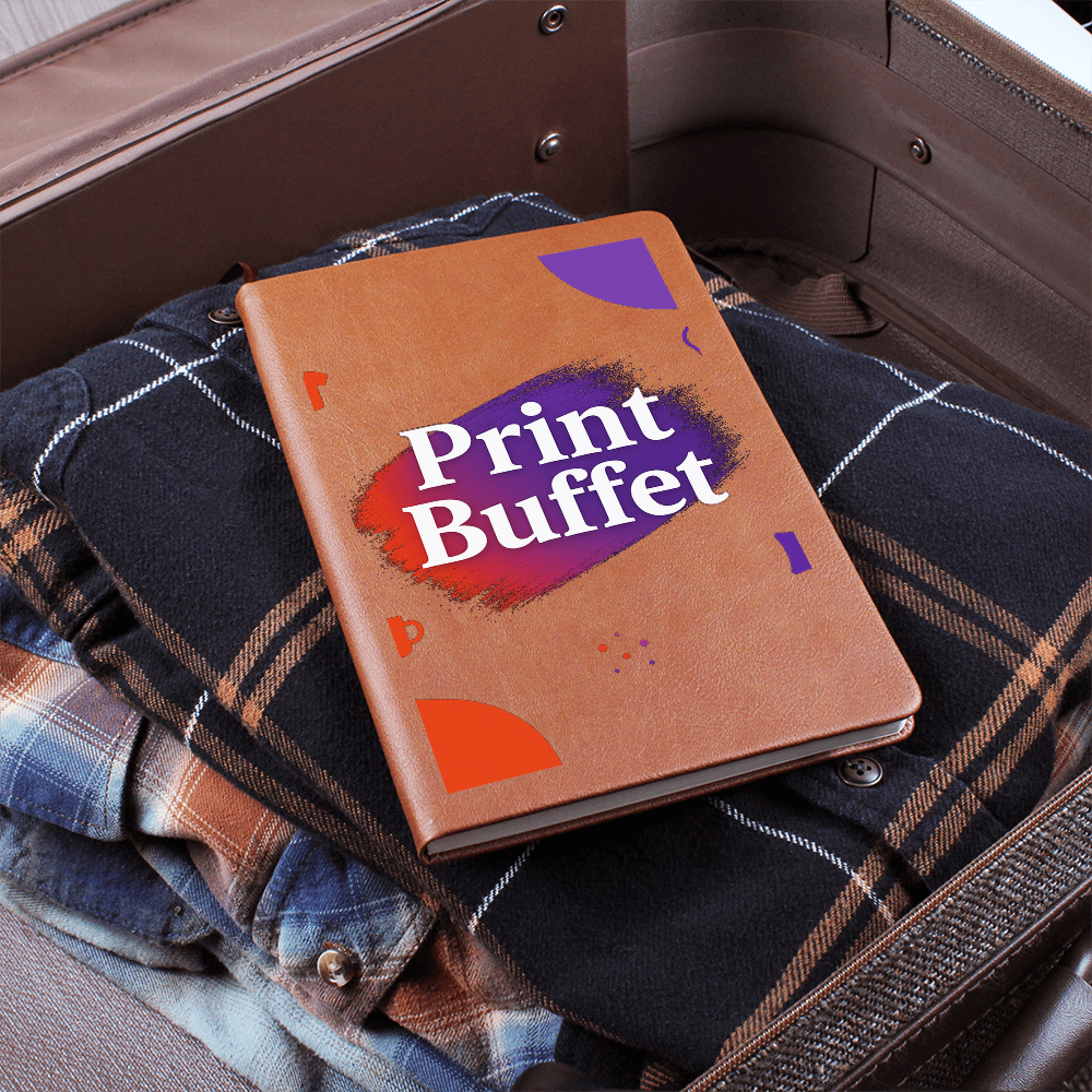 Brown notebook with Print Buffet text on folded plaid shirts inside open suitcase
