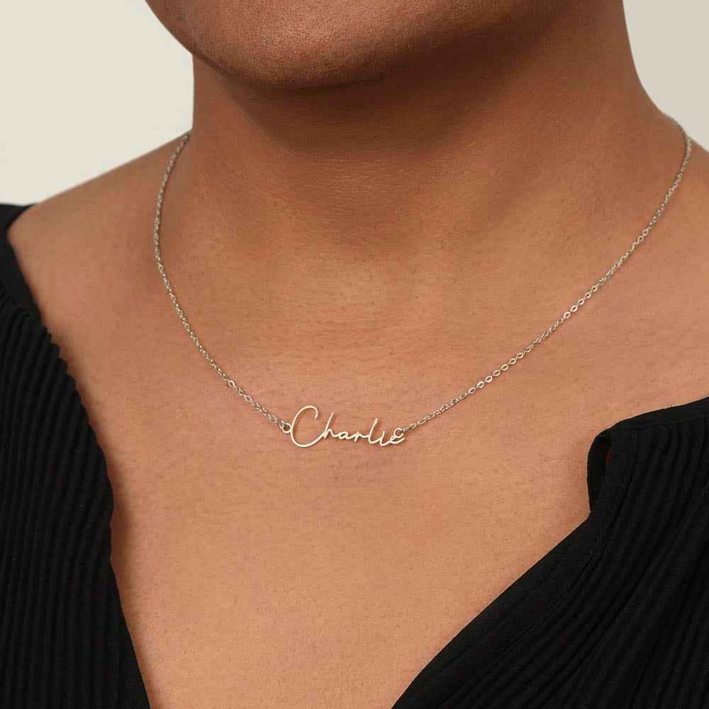 Close-up of a person wearing a silver name necklace with the word 'Charlie' on a delicate chain