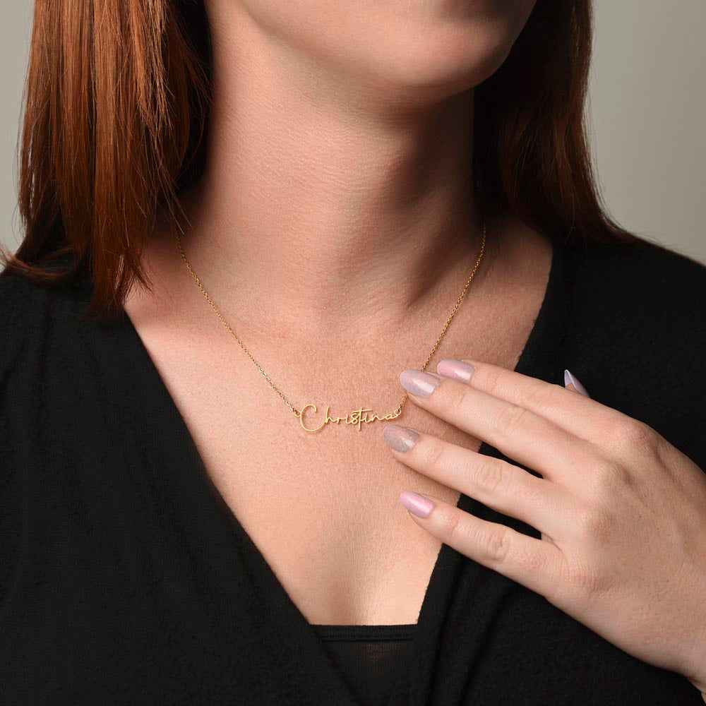 Close-up of woman wearing gold personalized name necklace 'Christina' with black top and manicured nails