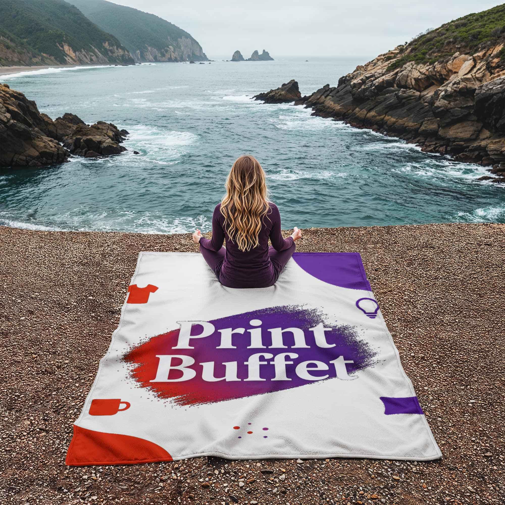 Woman meditating on Print Buffet branded blanket by rocky seaside with waves and cliffs