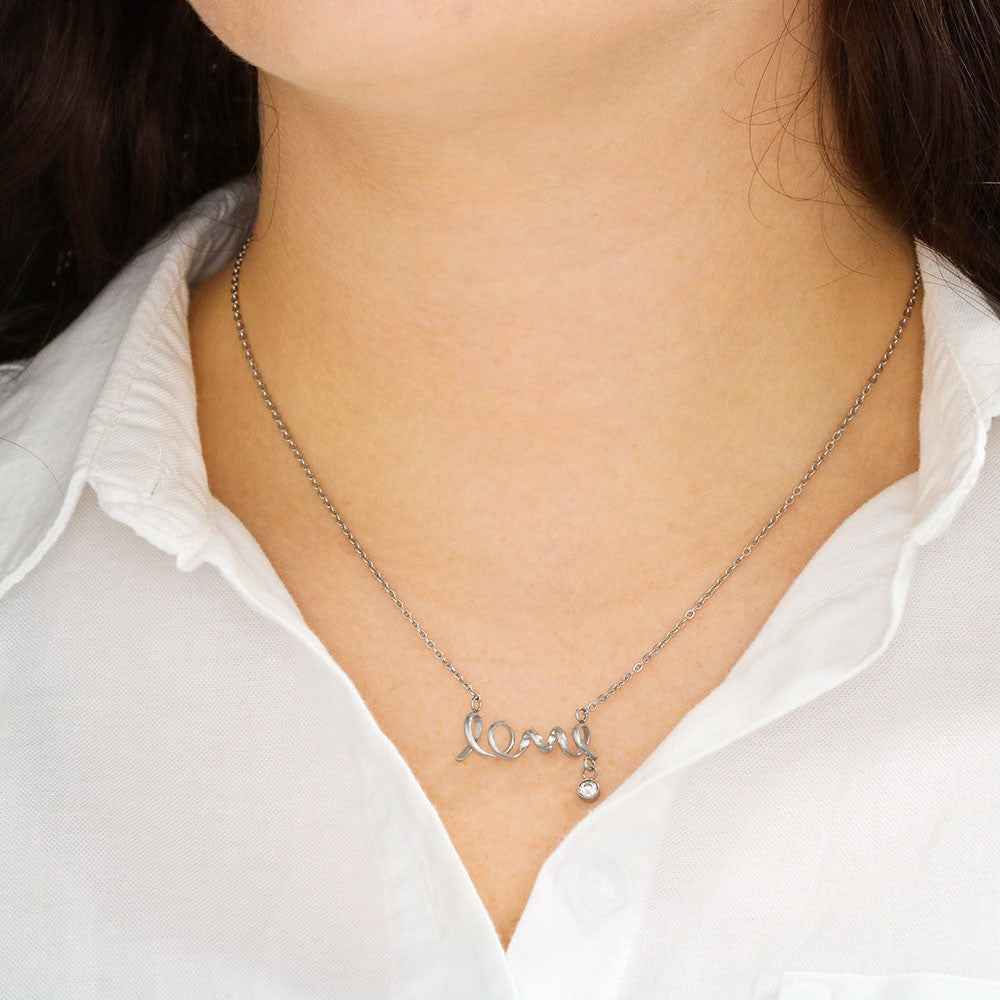 Close-up of a woman wearing a silver necklace with the word 'love' and a small dangling crystal pendant