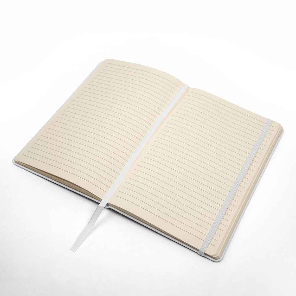 Open beige lined notebook with white ribbon bookmark and elastic band on white background