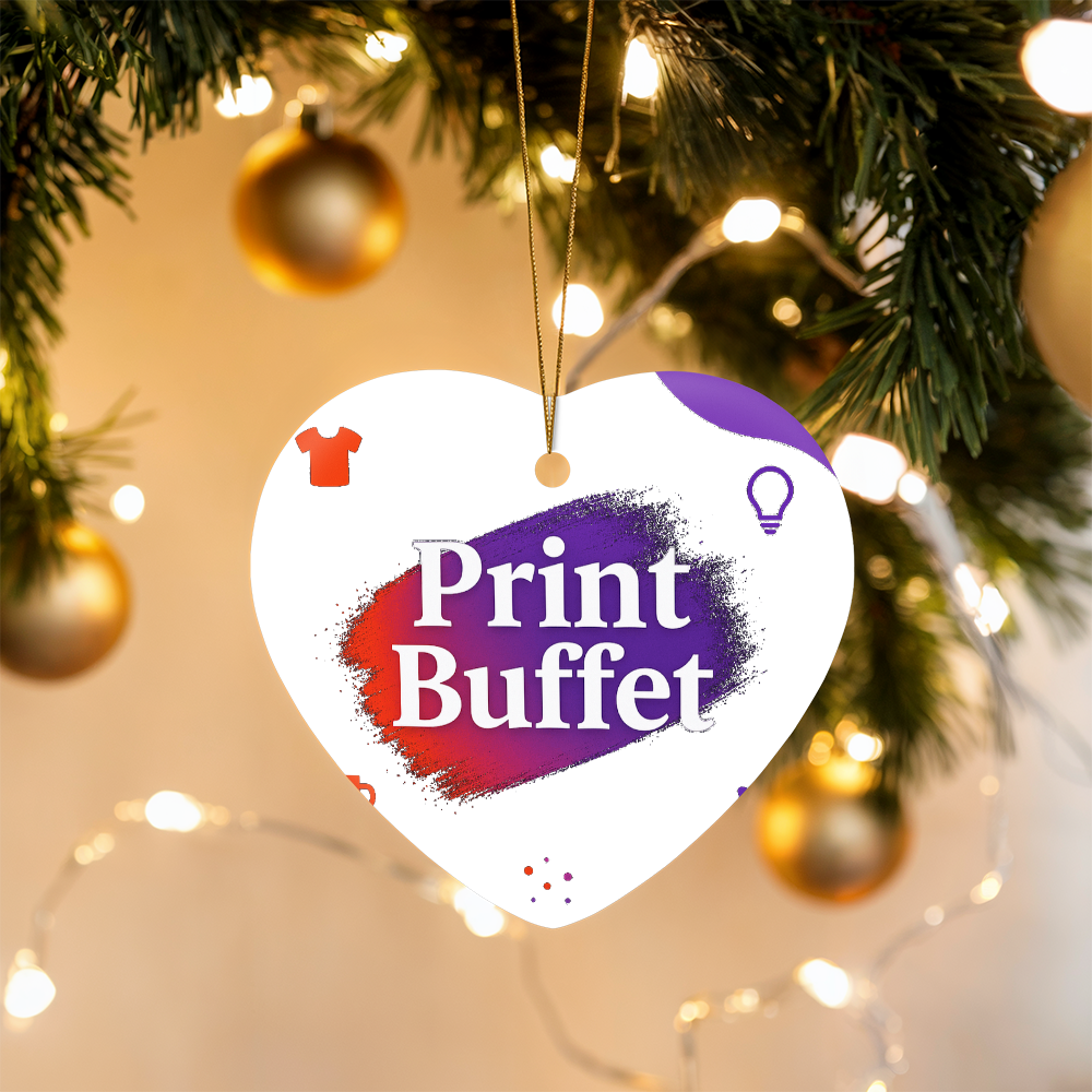 Heart-shaped Christmas ornament with Print Buffet logo hanging on decorated tree with golden baubles and lights
