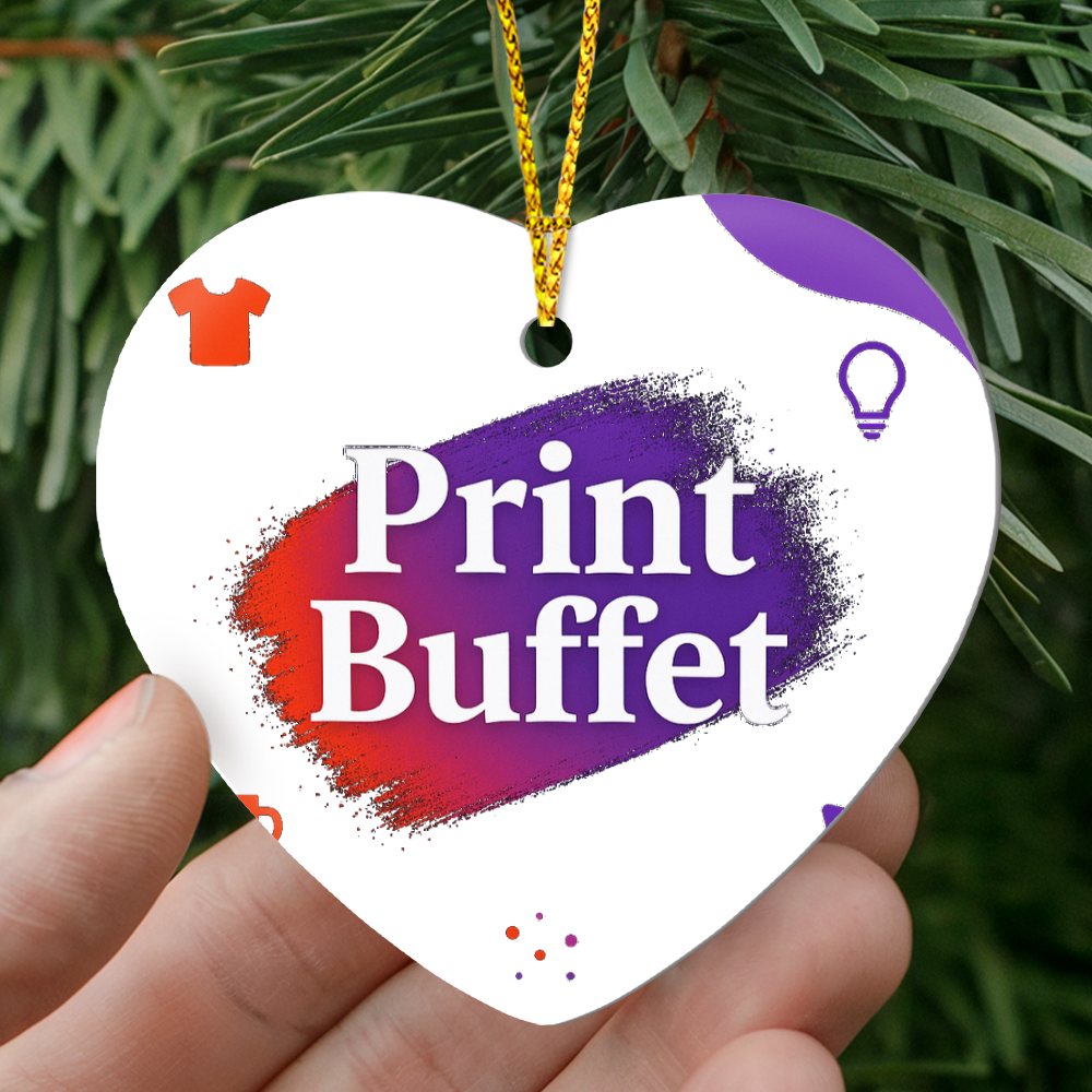 Hand holding a heart-shaped Print Buffet tag with red and purple brush strokes, hanging on a green pine branch