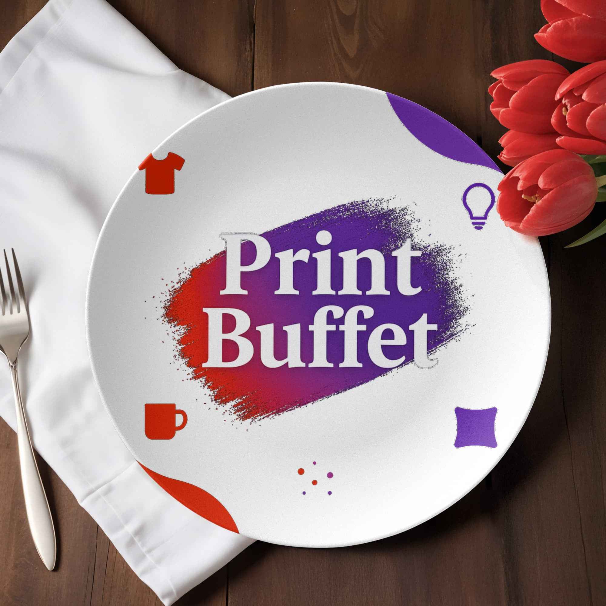 White plate with colorful Print Buffet logo, fork on white napkin, and red tulips on wooden table
