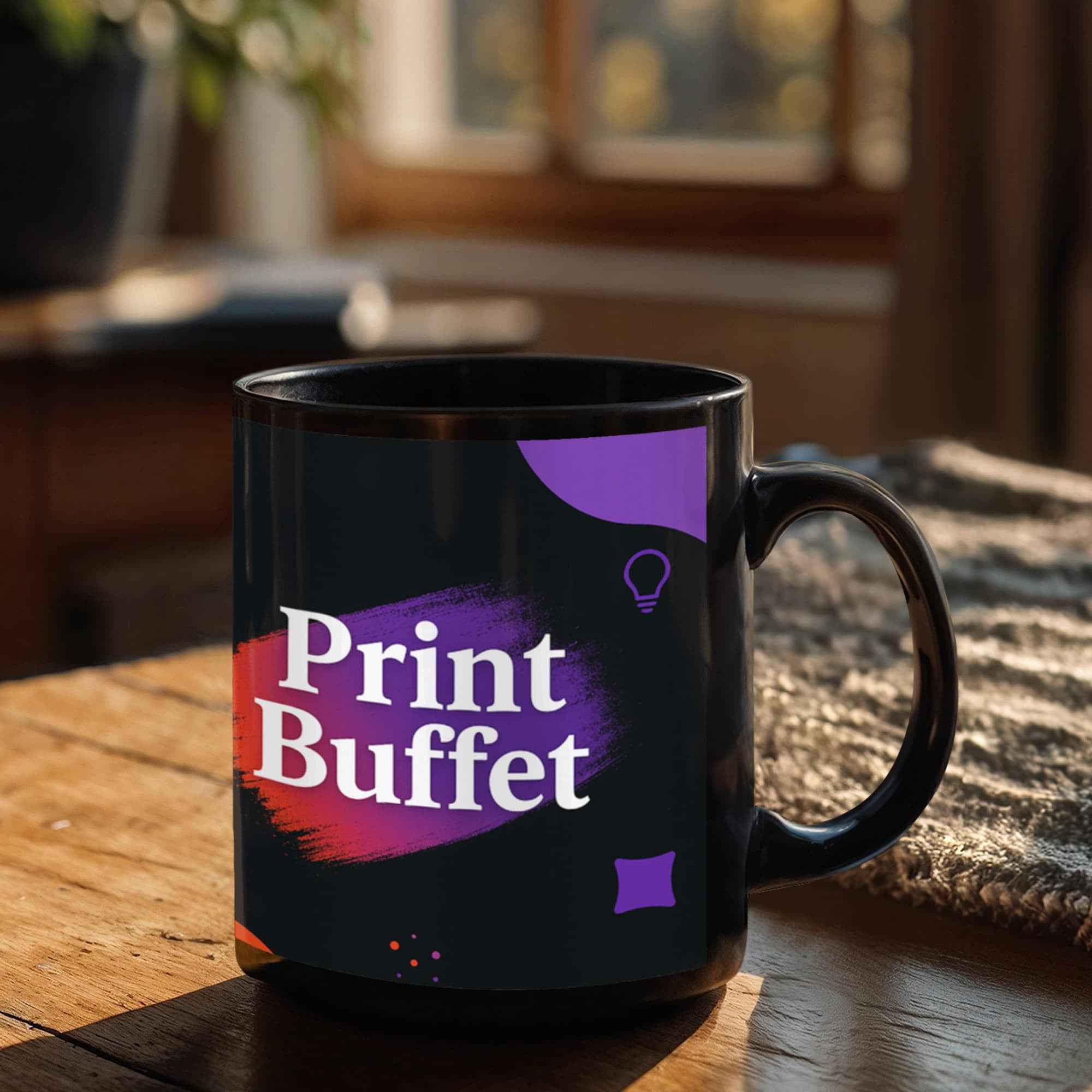 Black mug with colorful Print Buffet logo on wooden table in cozy indoor setting