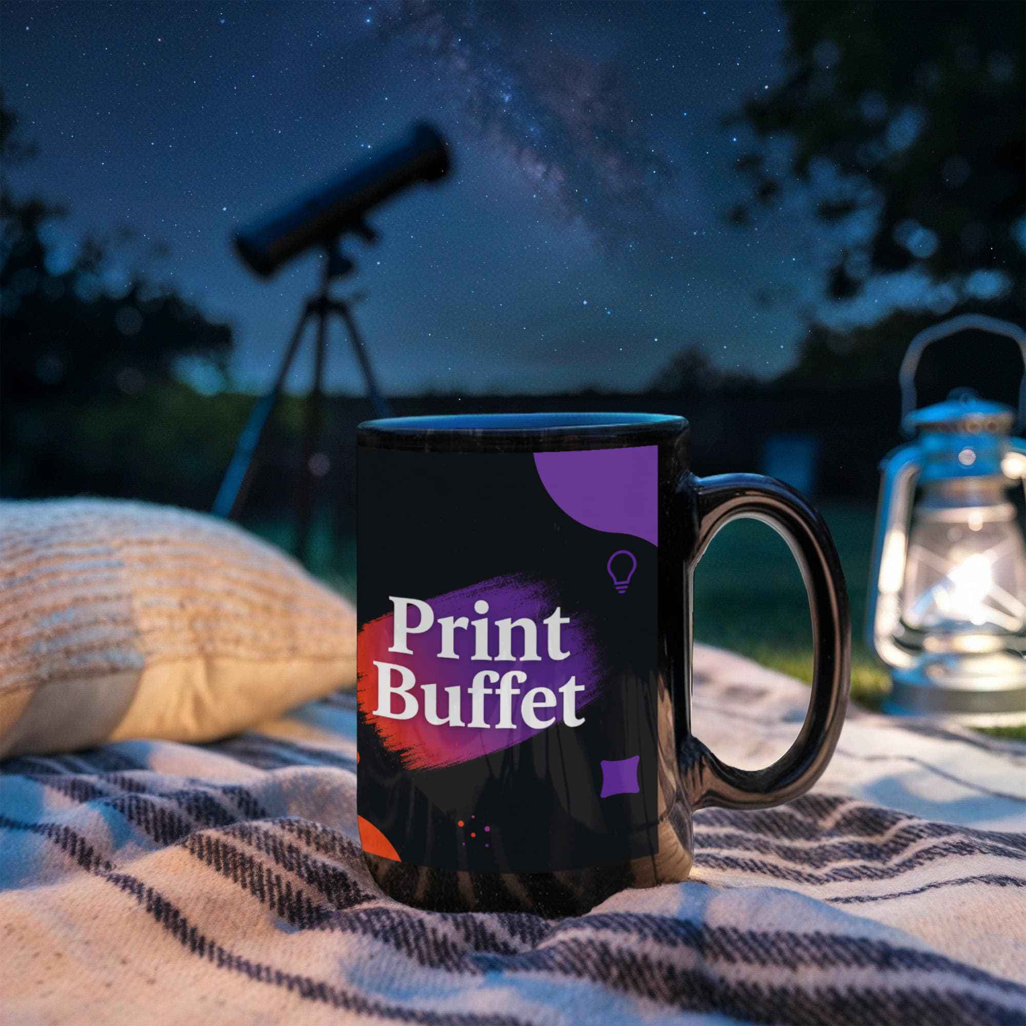 Black Print Buffet mug on blanket with pillow, telescope, and lantern under starry night sky