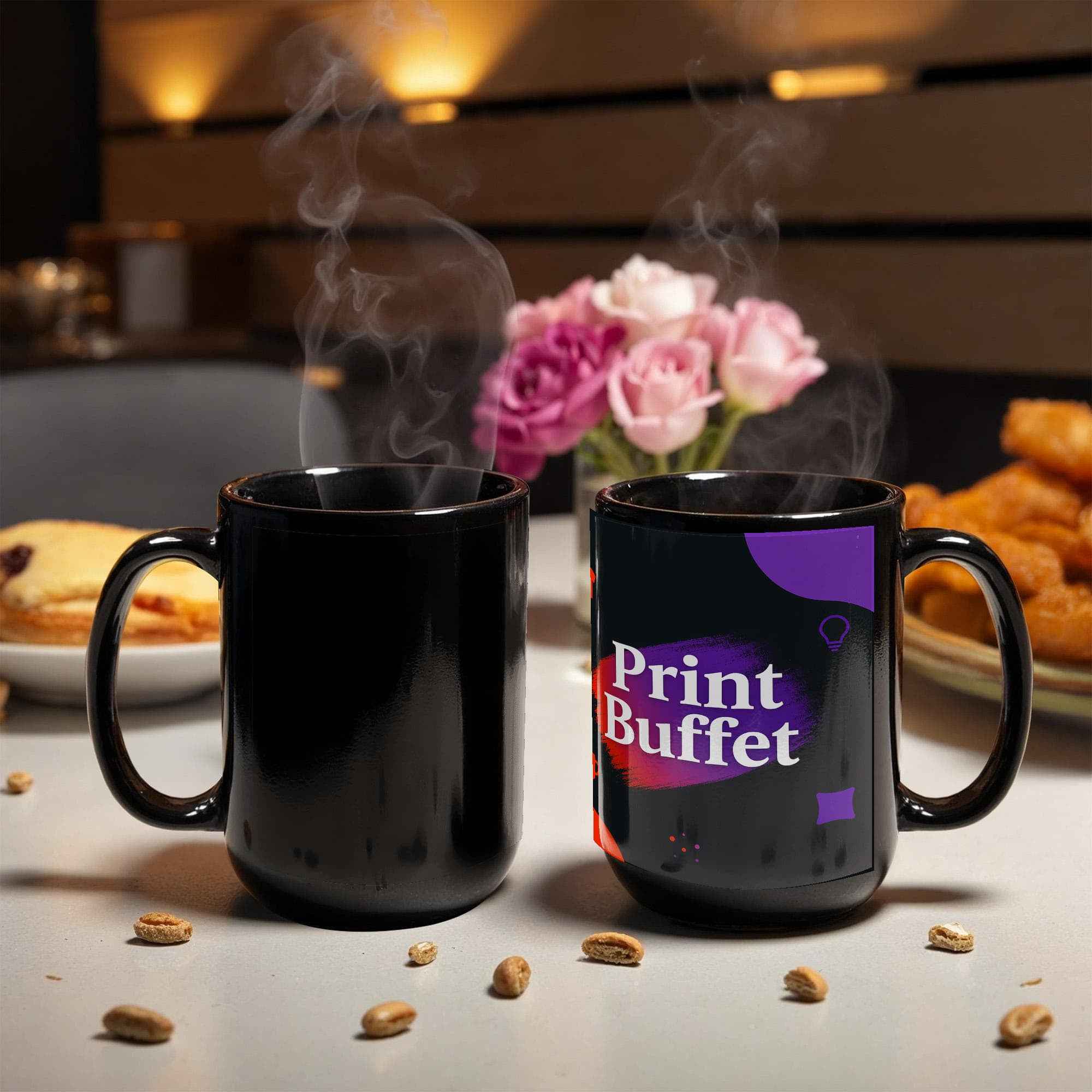 Two steaming black coffee mugs on a table with one mug displaying a colorful Print Buffet logo, flowers and snacks in background