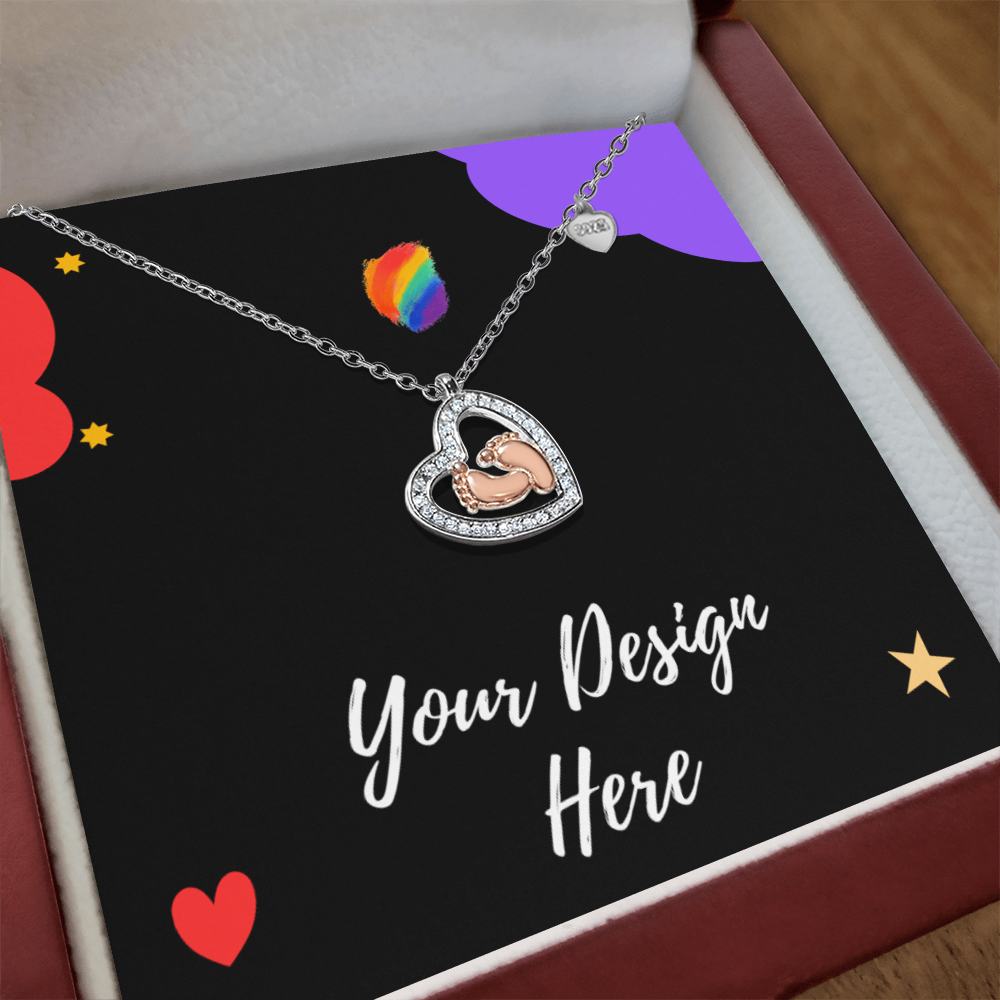 Heart-shaped necklace with baby feet charm and rhinestones, displayed on black card with colorful hearts